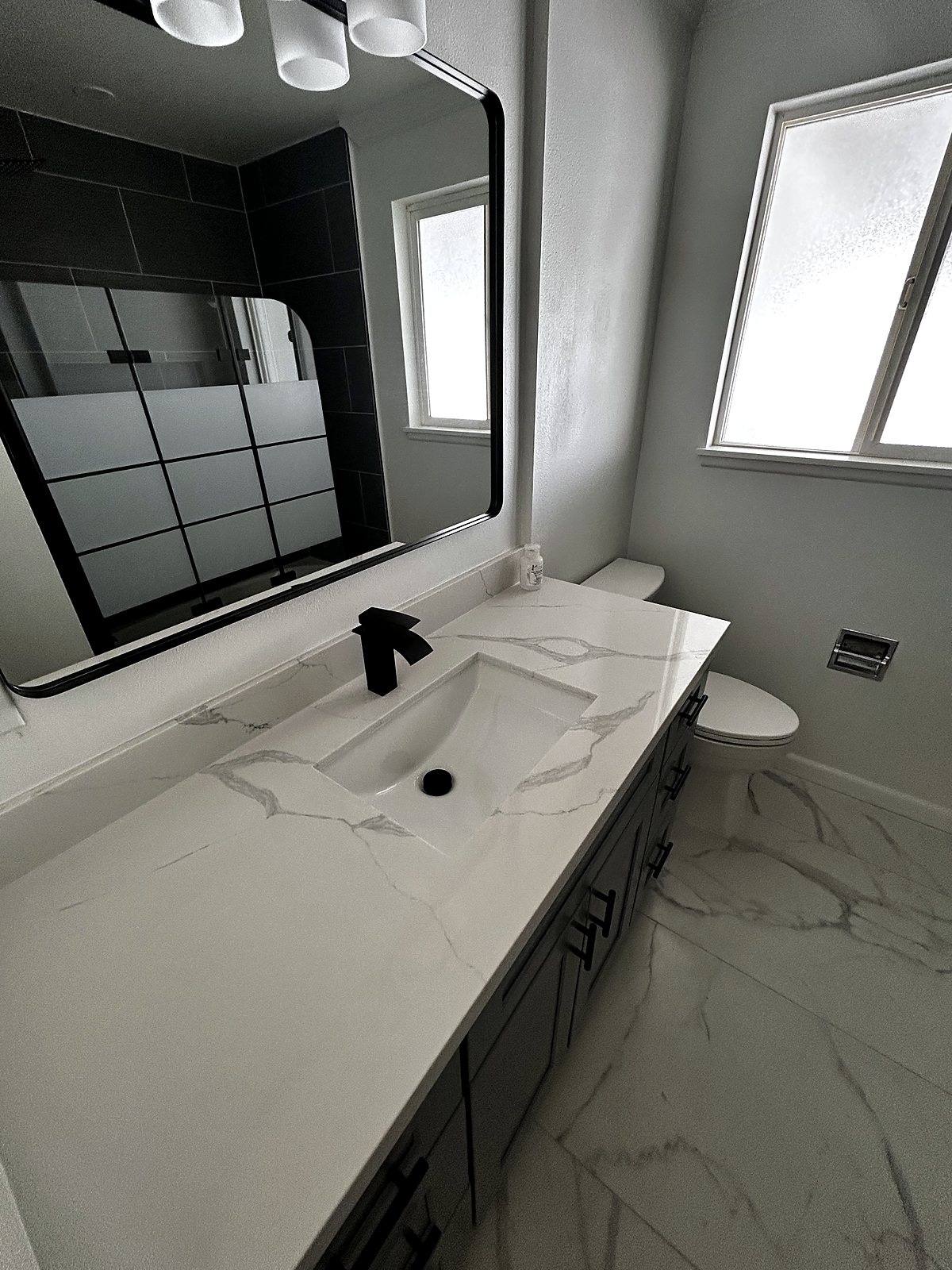 Bathroom renovation with quartz countertop and dark tile, King County.