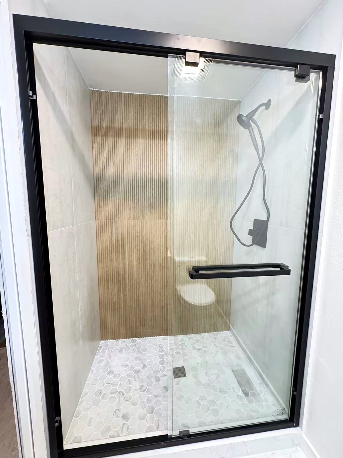 Modern walk-in shower with black-framed glass doors and marble tile, King County.