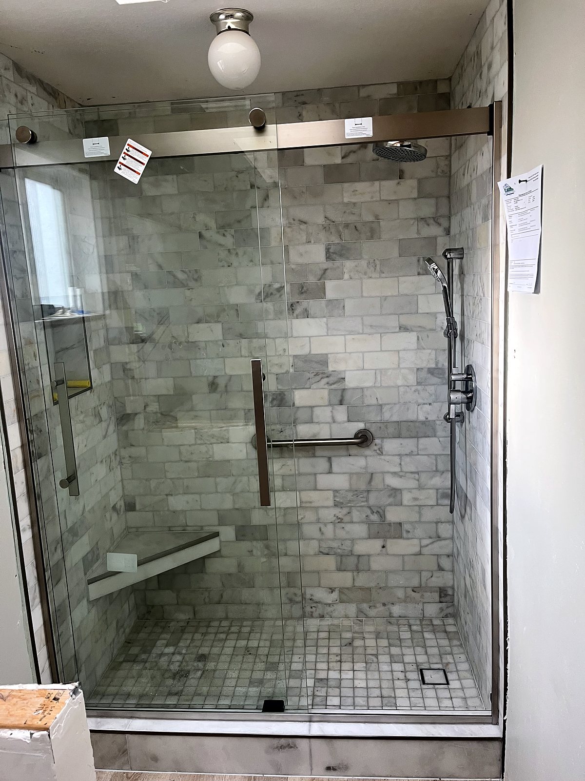 Walk-in shower with marble tile and frameless doors, King County.