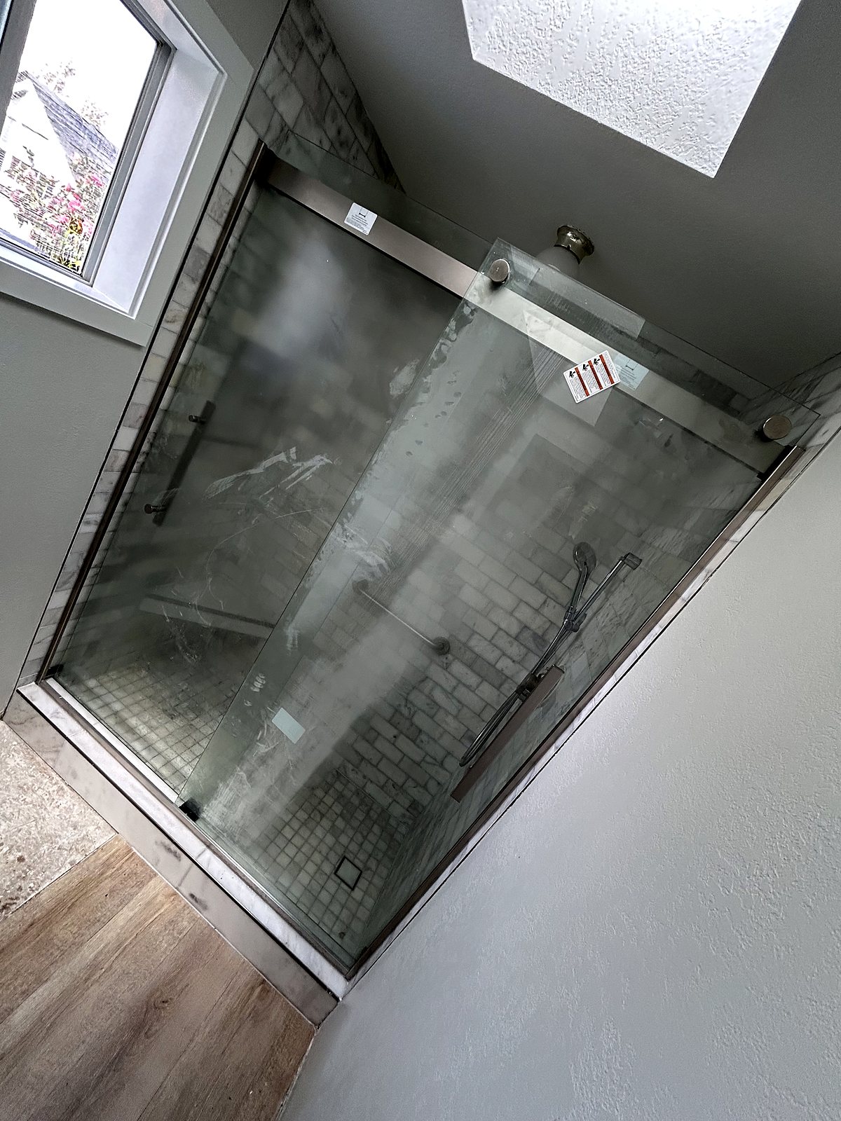 Frameless glass shower enclosure with subway tile and mosaic floor, King County.
