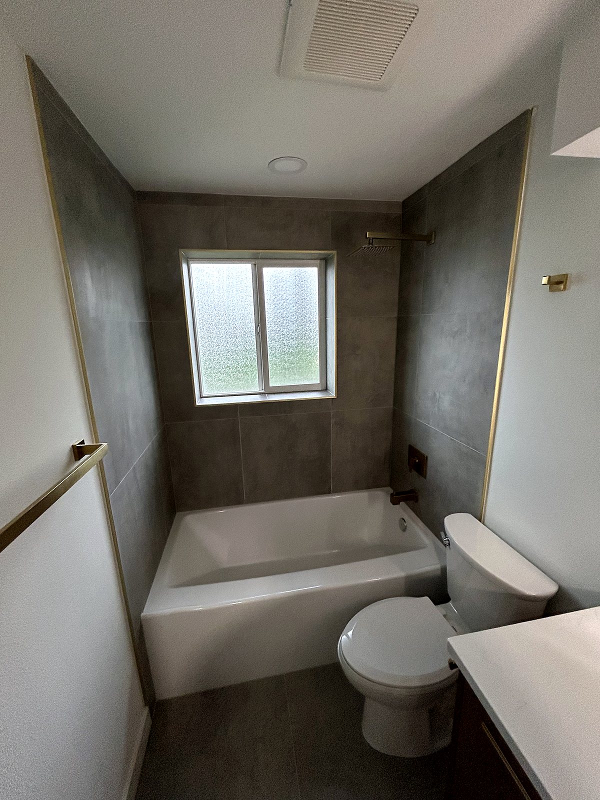 Renovated bathroom with gray tile shower surround and white tub, King County.