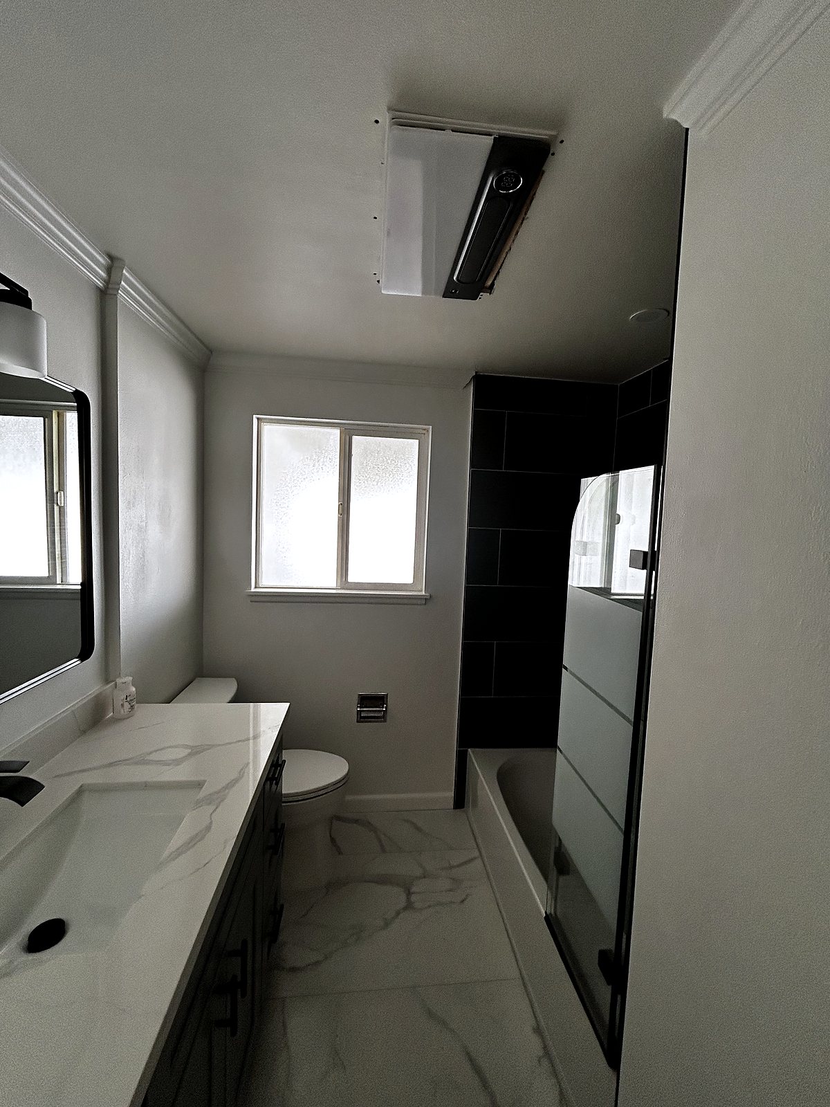 Modern bathroom renovation with marble tile floor and black fixtures, King County.