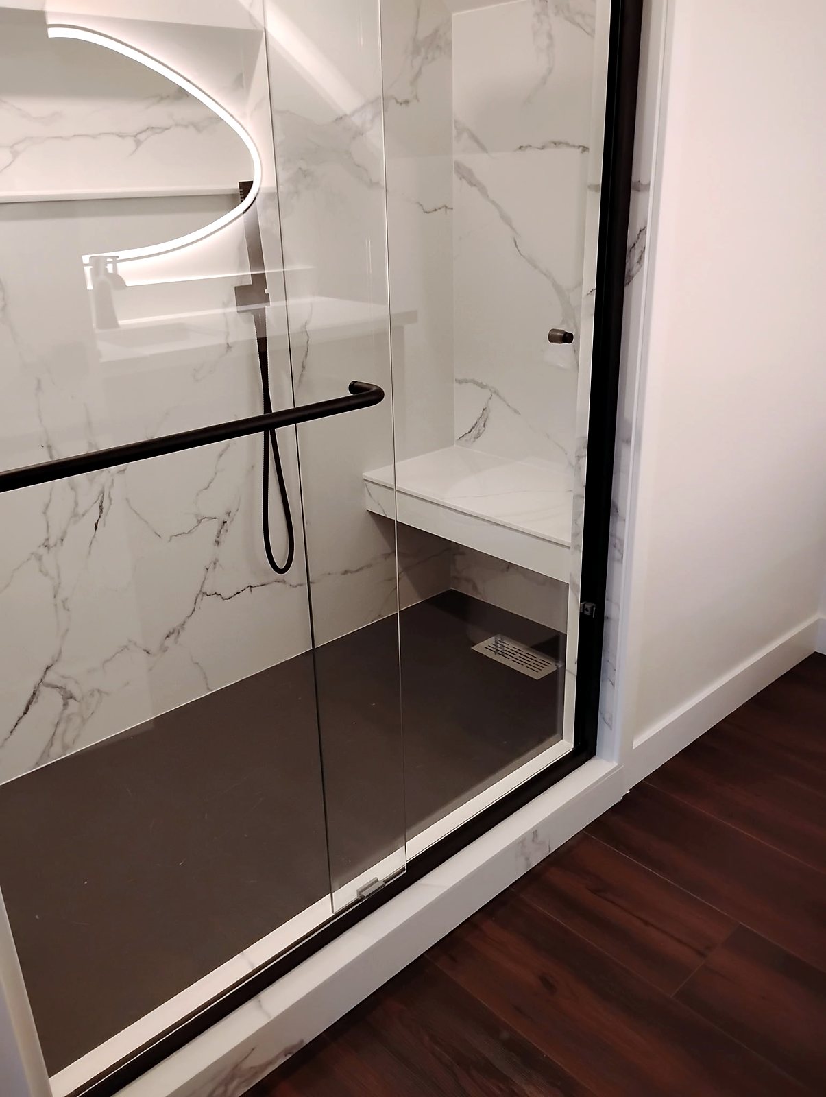 Modern walk-in shower with black frame doors and marble tile in King County.