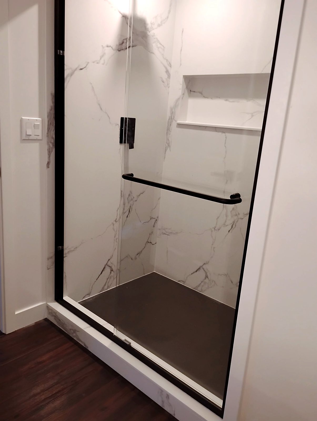 White marble tile walk-in shower with black frame glass door, King County.