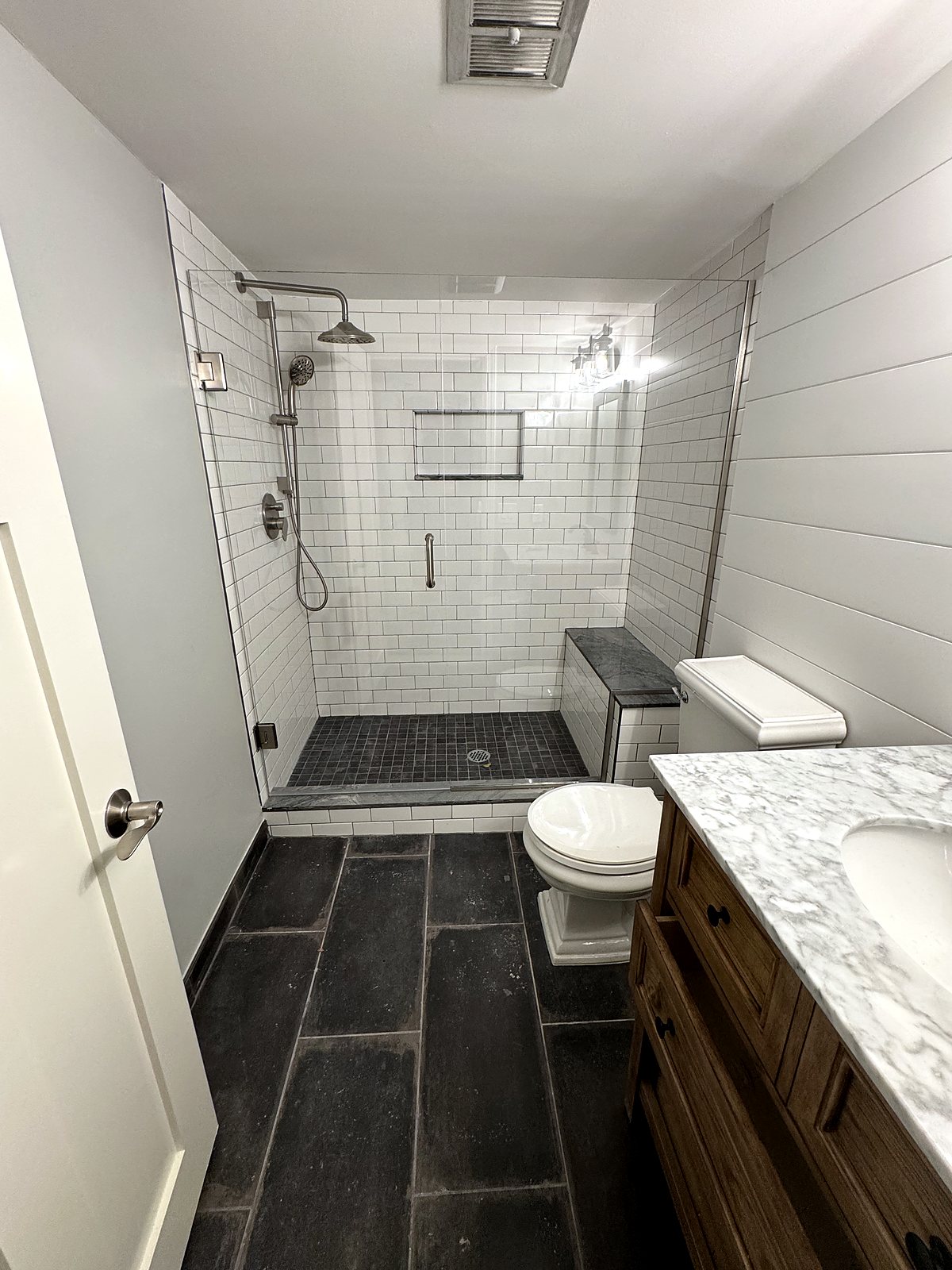 Renovated bathroom with subway tile shower and slate flooring, King County.