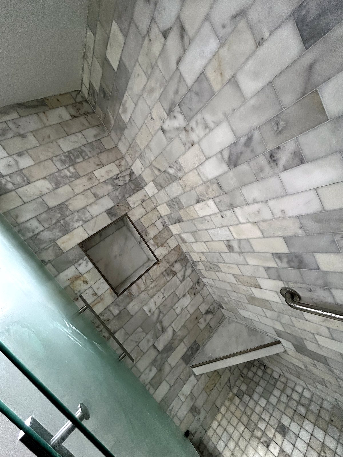 Herringbone marble tile shower with built-in niche, King County.