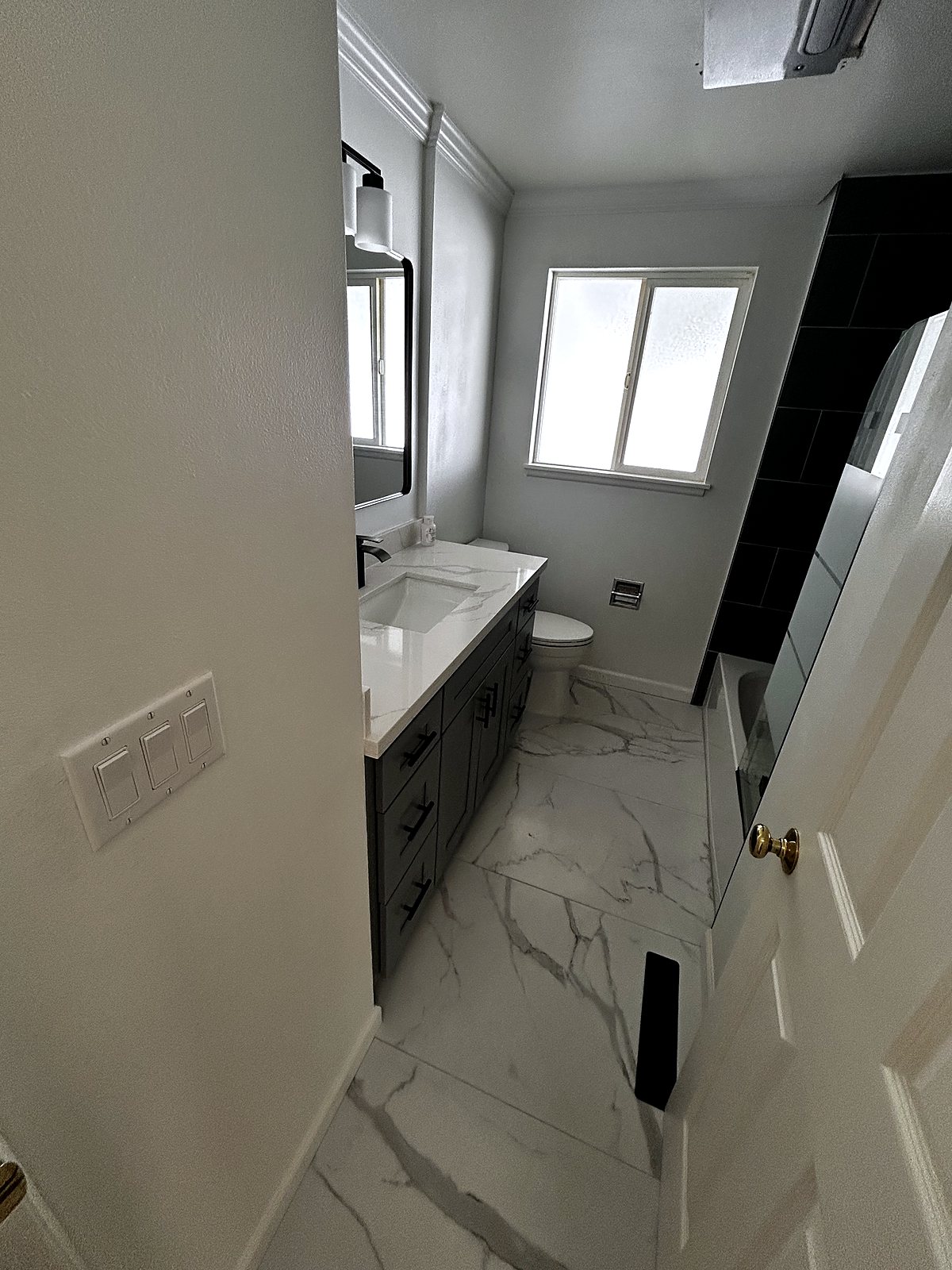 Renovated bathroom with dark vanity and marble tile, King County.