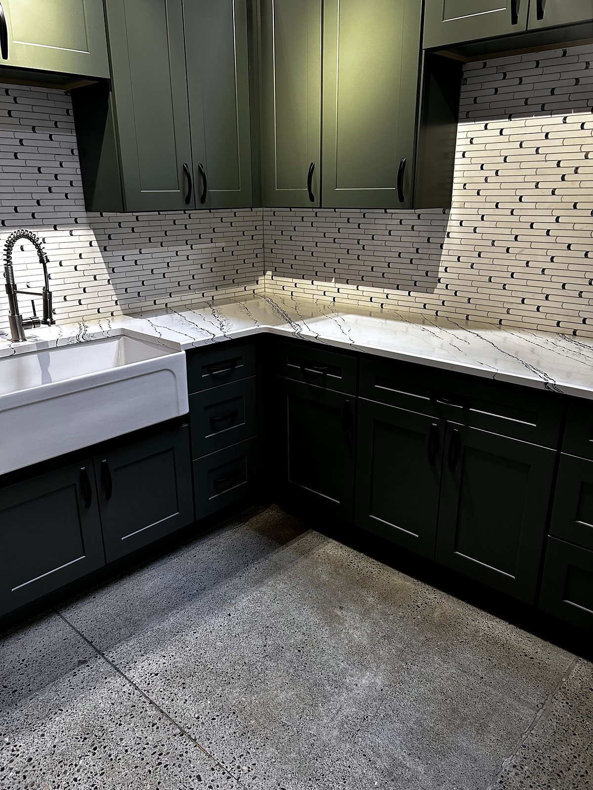 Dark green kitchen cabinets with marble countertops and concrete floors, King County.